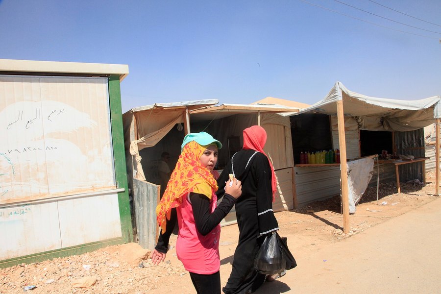 Two Syrian refugee women walk past market stalls in the Za'atari refugee camp in northern Jordan.