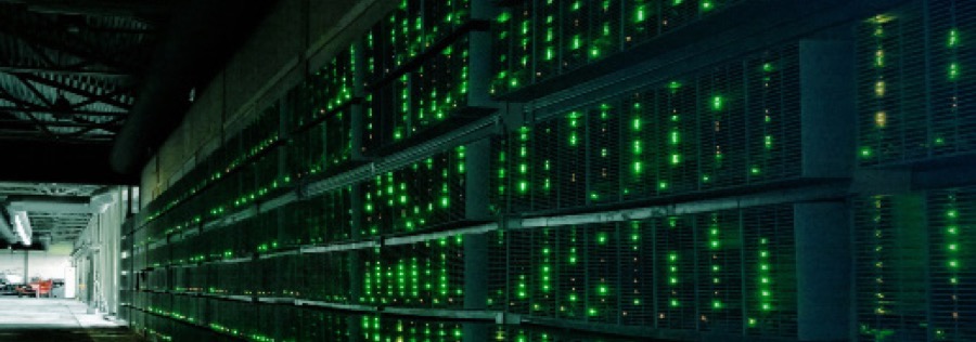 Racks of cryptocurrency mining computers glowing green in a dark warehouse.